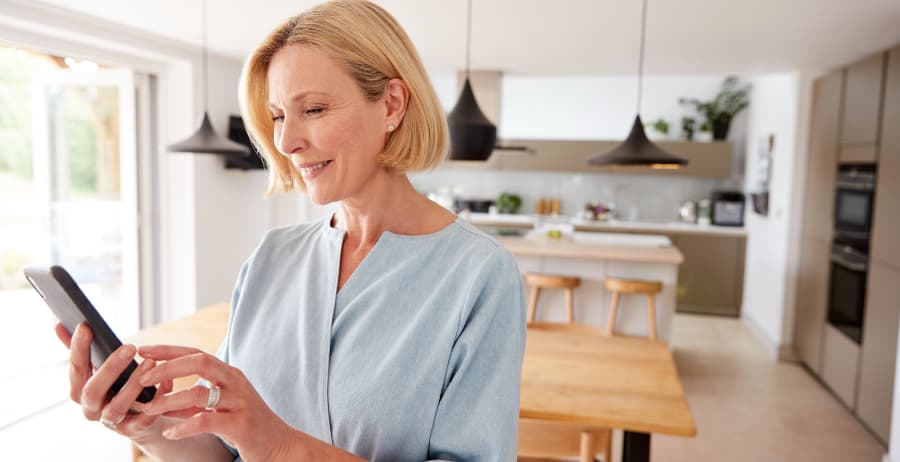 Resident holding a smartphone in a modern home